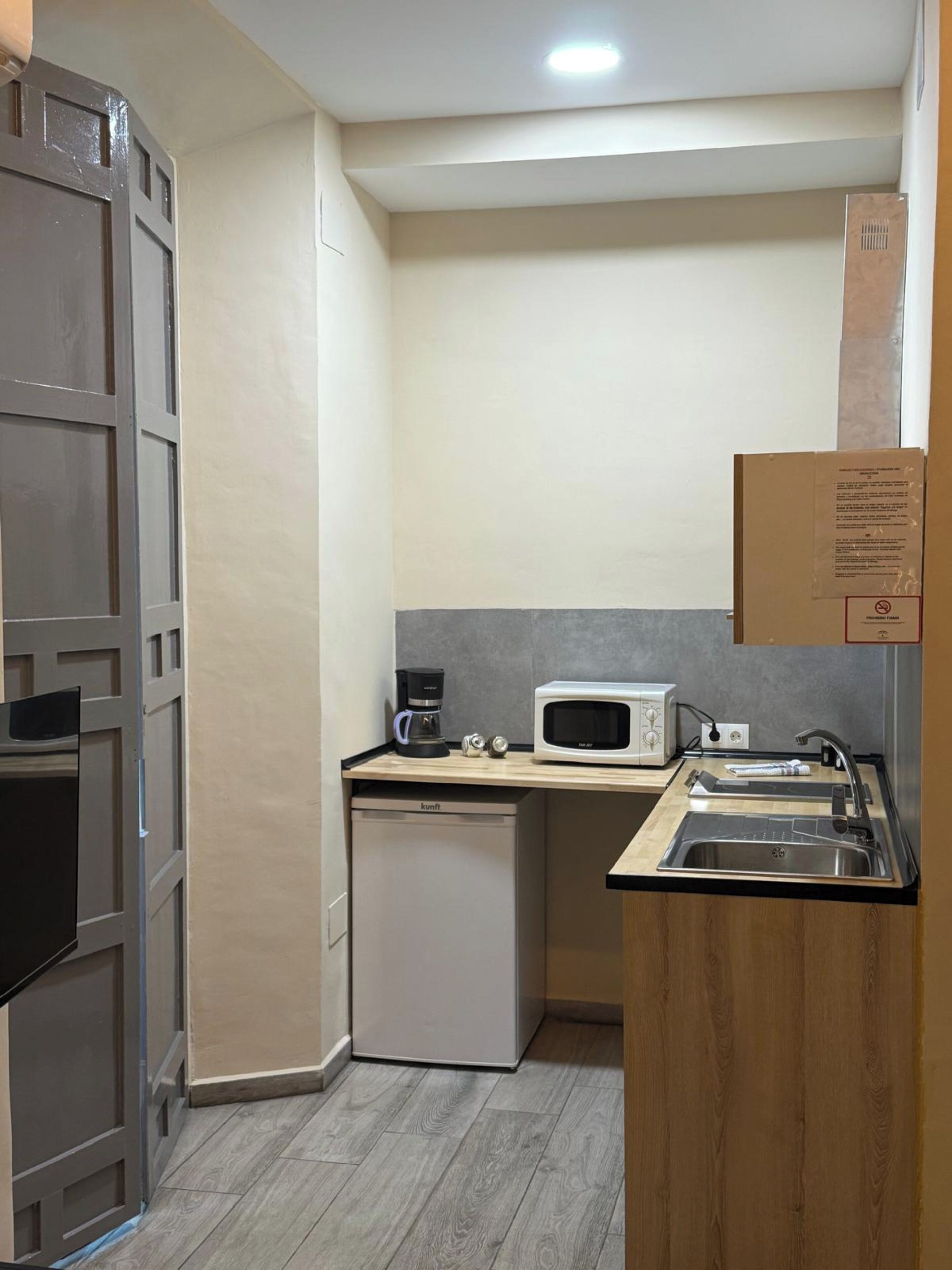 A compact kitchen with a microwave, coffee maker, and a small dishwasher.