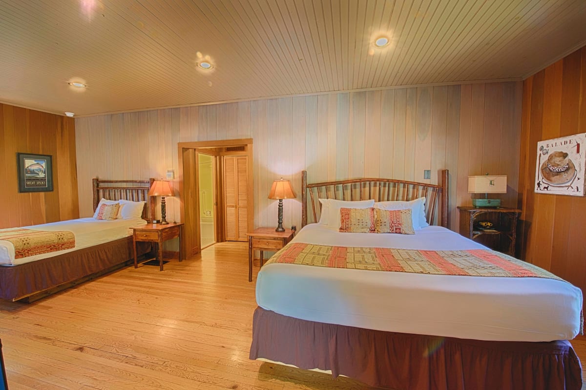 A hotel room with two beds, wooden floors, and a wooden ceiling.