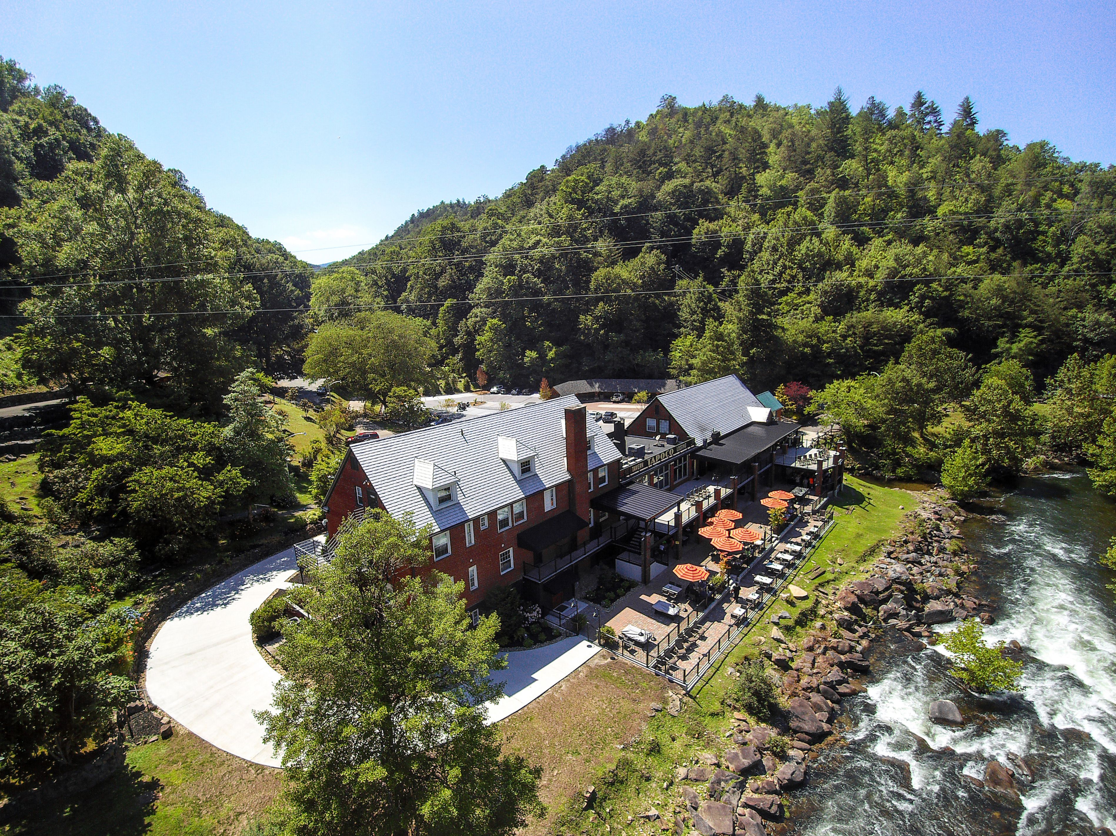 A riverside hotel with outdoor seating and a view of the river.