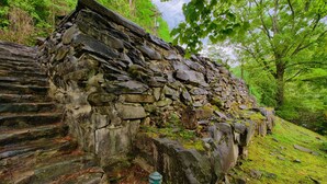 A stone staircase leading up to a rustic stone structure in a forested area. - Historic Tapoco Lodge Resort (Robbinsville)