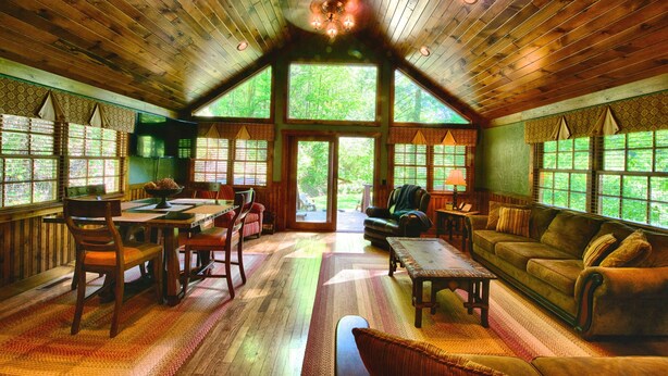 A spacious, wooden-floored living room with a high ceiling, large windows, and a fireplace. - Historic Tapoco Lodge Resort (Robbinsville)