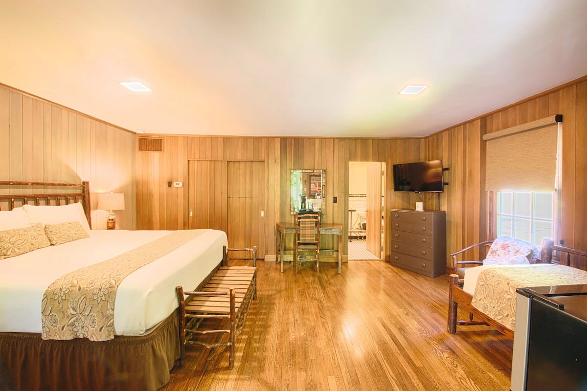 A hotel room with a large bed, a desk, a television, and a dresser.