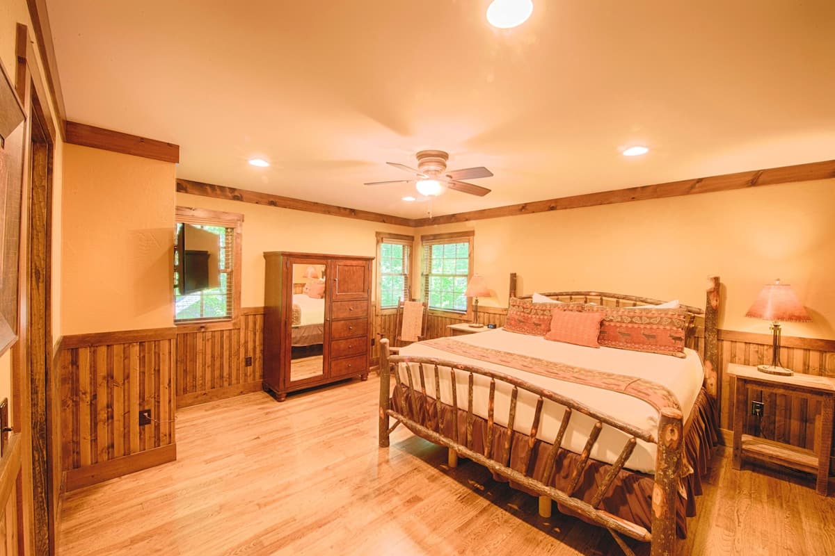 A bedroom with a wooden bed, a ceiling fan, and a wooden wardrobe.