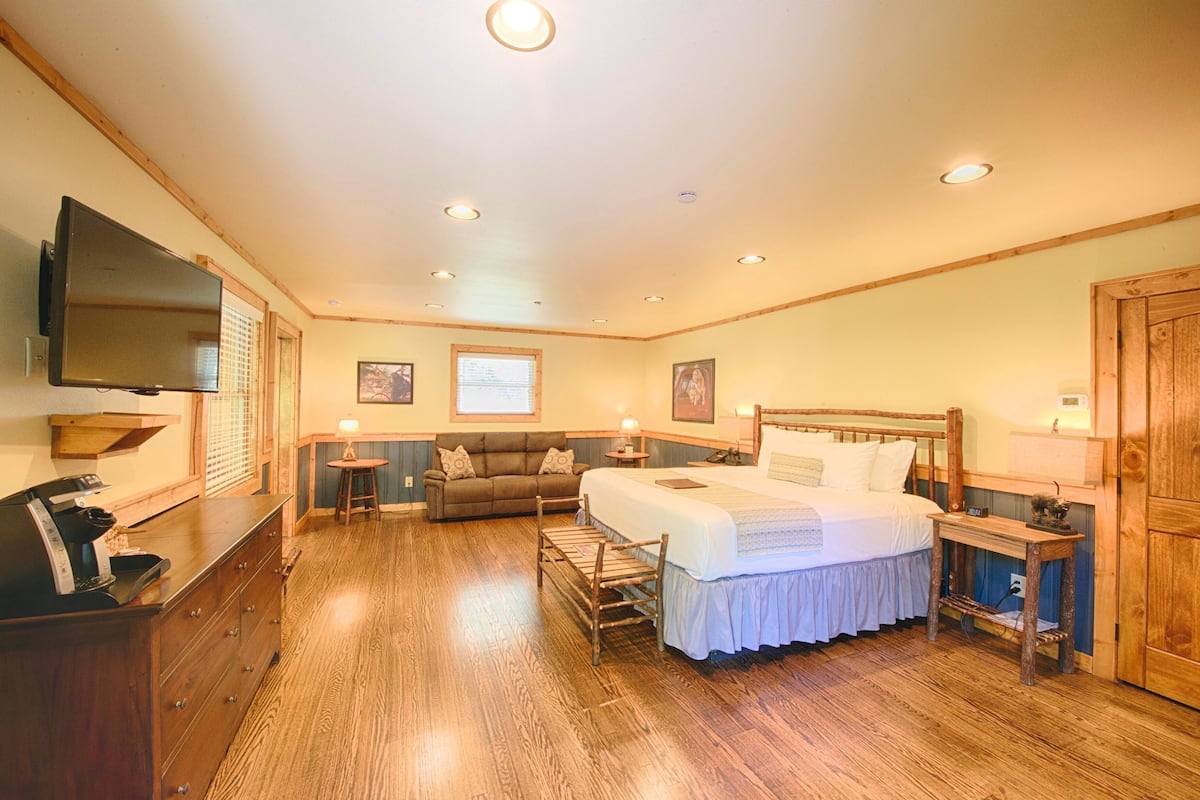 A bedroom with a bed, a TV, a desk, and a chair.