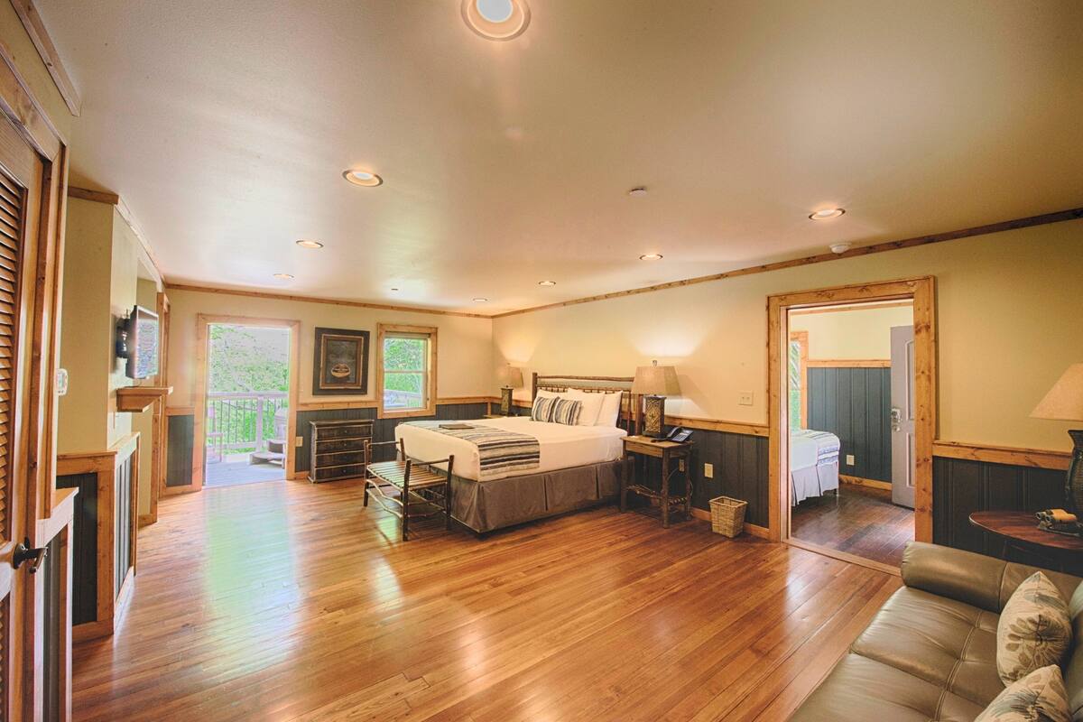 A spacious bedroom with a large bed, bedside tables, and a view of a balcony.