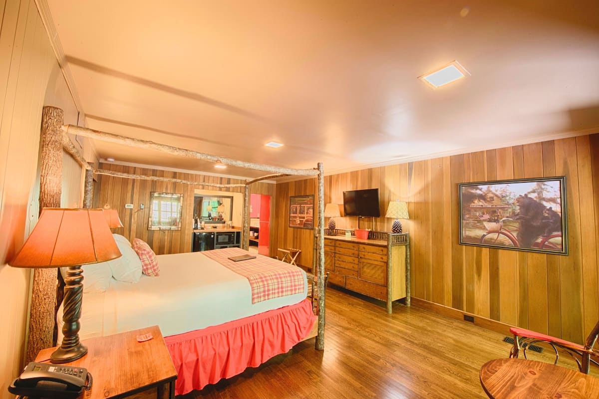 A cozy bedroom with a bed, bedside table, lamp, and a television.