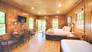 A wooden-paneled room with a bed, a desk, and a television. - Historic Tapoco Lodge Resort (Robbinsville)