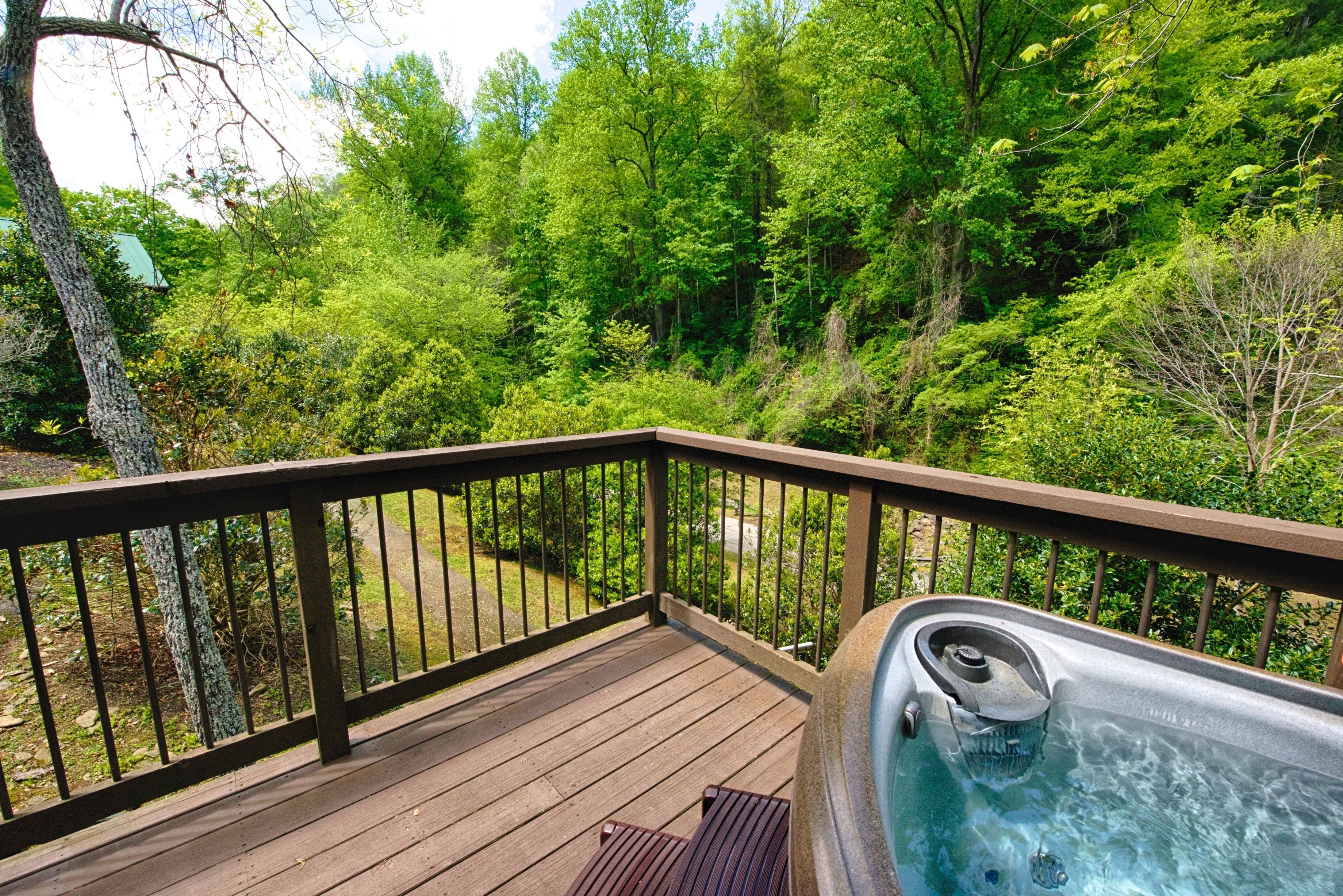 A wooden deck with a hot tub and a view of a forested area.