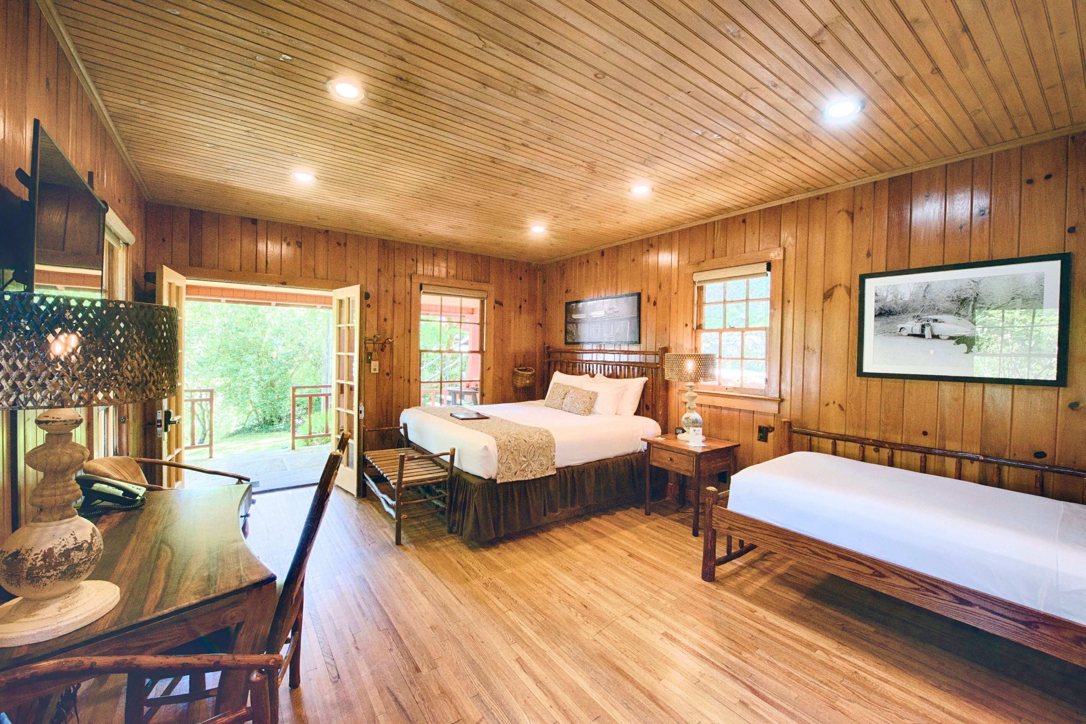 Ein Schlafzimmer einer Holzhütte mit einem Bett, einem Schreibtisch und einem Stuhl.