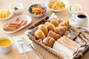 A breakfast spread with various pastries, meats, and condiments on a wooden table. - Hotel Matsumoto Yorozuya (Matsumoto)