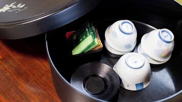 A black container with a lid, containing a stack of green and yellow cards, and two white cups with blue lids.