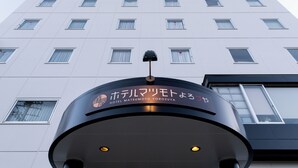 L'entrée de l'hôtel Matsumoto Yorozuya présente un design moderne et offre une vue dégagée sur la façade de l'immeuble.