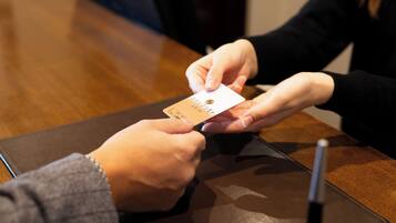 A person holding a card, possibly for payment or identification, at a table with a pen and a notebook.