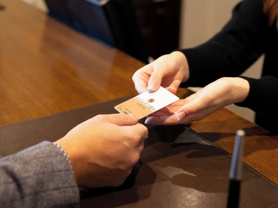 A person holding a card, possibly for payment or identification, at a table with a pen and a notebook.