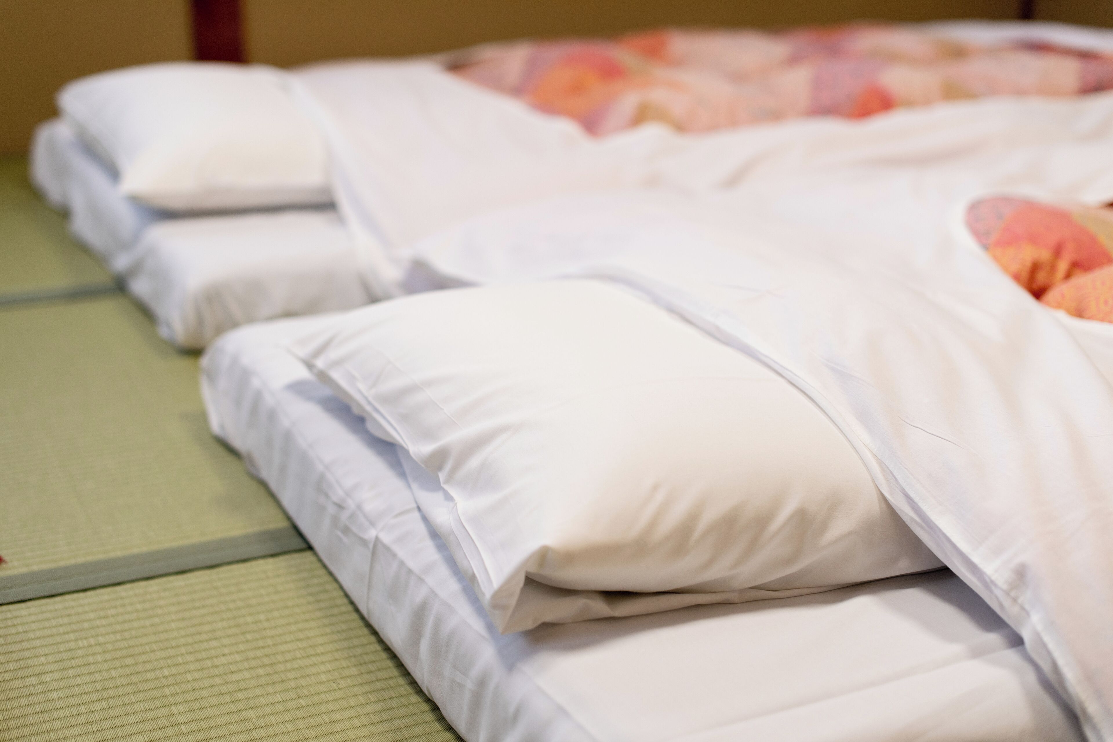 A neatly made bed with white bedding and a floral-patterned blanket.