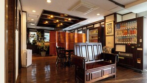 L’intérieur d’un restaurant, avec des meubles en bois, un distributeur automatique et une plante en pot.