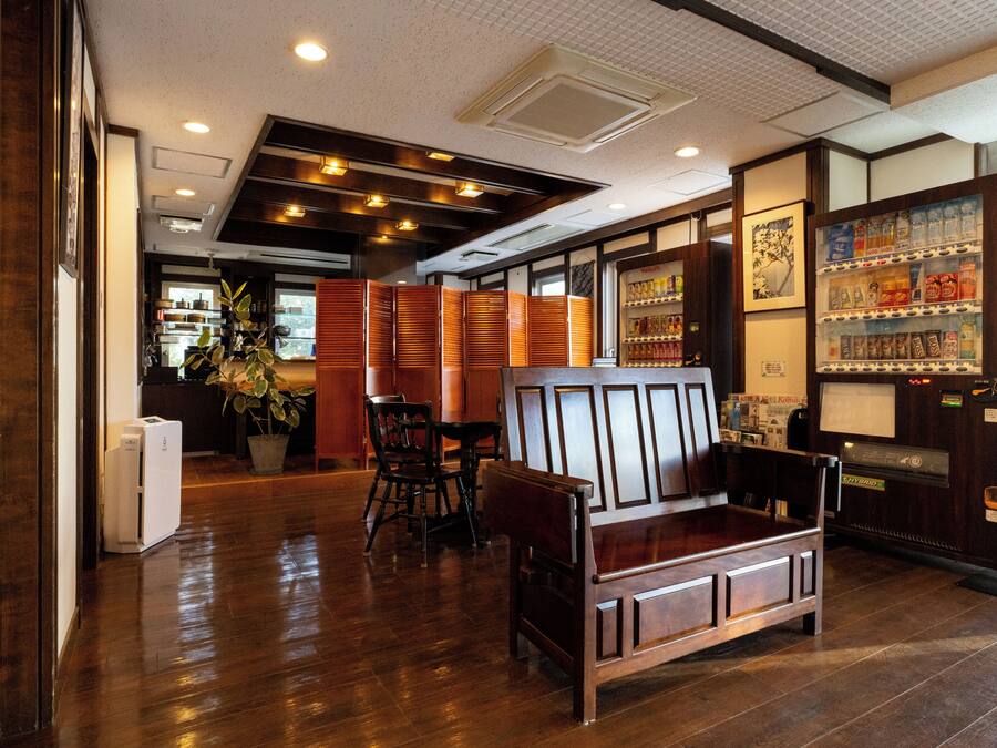 A restaurant interior with wooden furniture, a vending machine, and a potted plant.