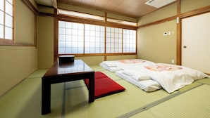 Une pièce de style japonais traditionnel, avec un sol recouvert de tatamis, une basse table en bois et des futons servant de lits.