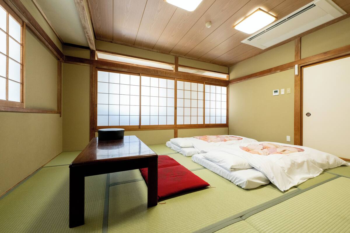 A traditional Japanese room with tatami flooring, a low wooden table, and futon beds.