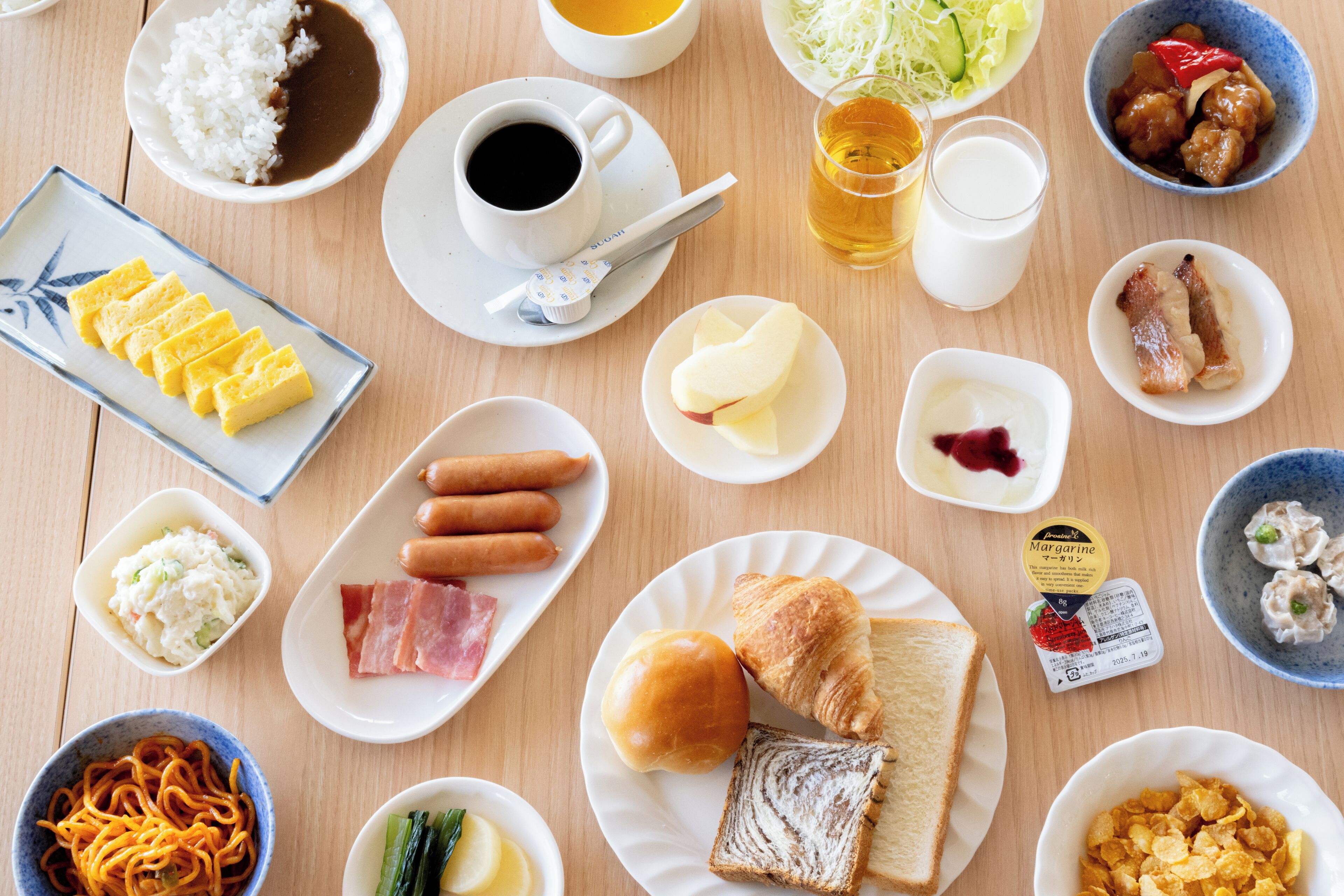 A variety of breakfast dishes including eggs, sausages, and bread on a wooden table.
