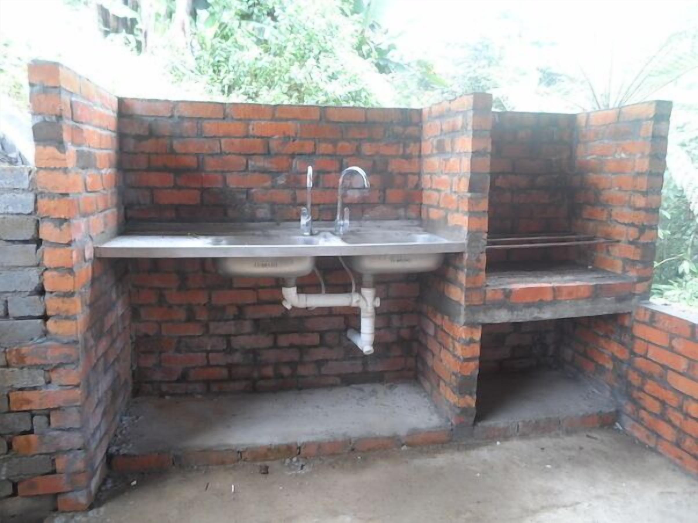 A brick-built outdoor kitchen with a sink and a built-in grill.