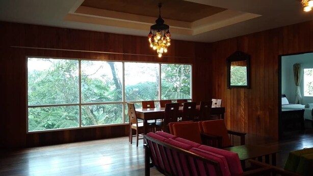 A dining area with a large window, wooden walls, and a chandelier.