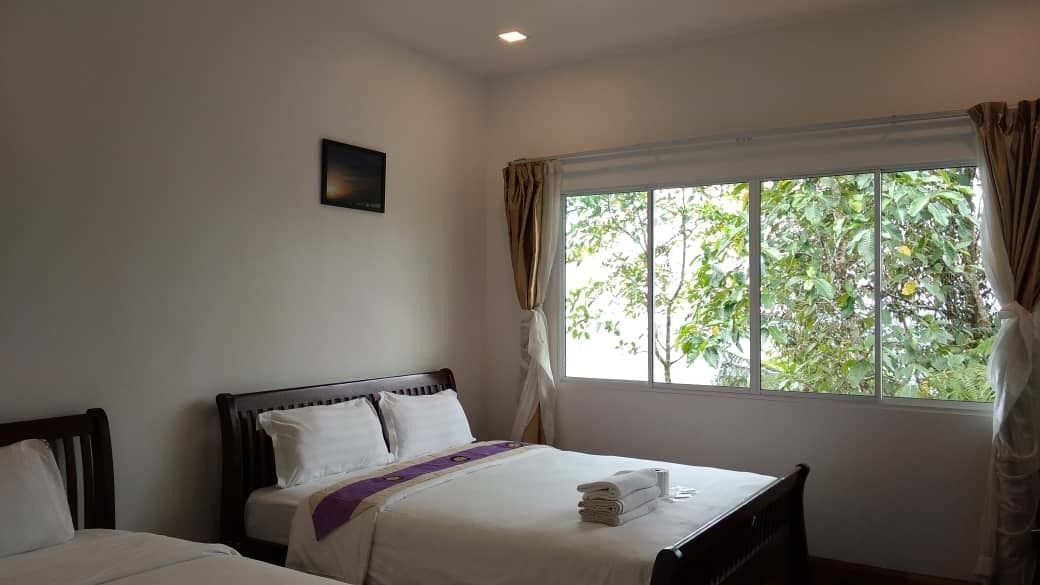 A hotel room with a bed, a window with curtains, and a small picture on the wall.