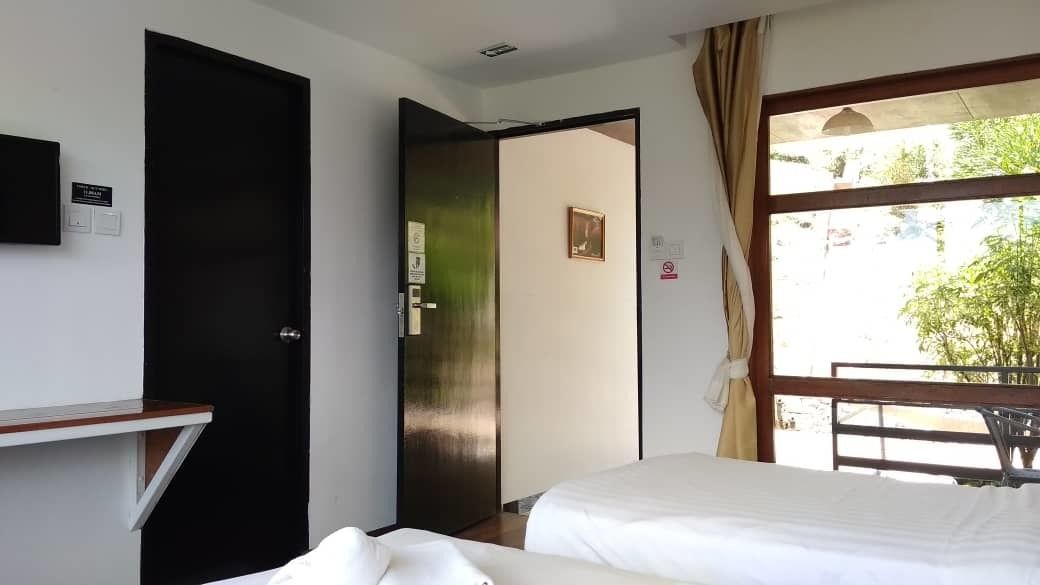 Une chambre d’hôtel avec un lit, un bureau, une fenêtre avec des rideaux et une porte donnant sur une autre pièce.
