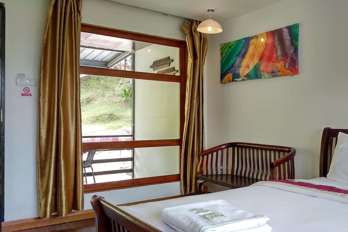 Une chambre d’hôtel avec un lit, une fenêtre avec des rideaux, un tableau au mur et une vue sur l’extérieur.