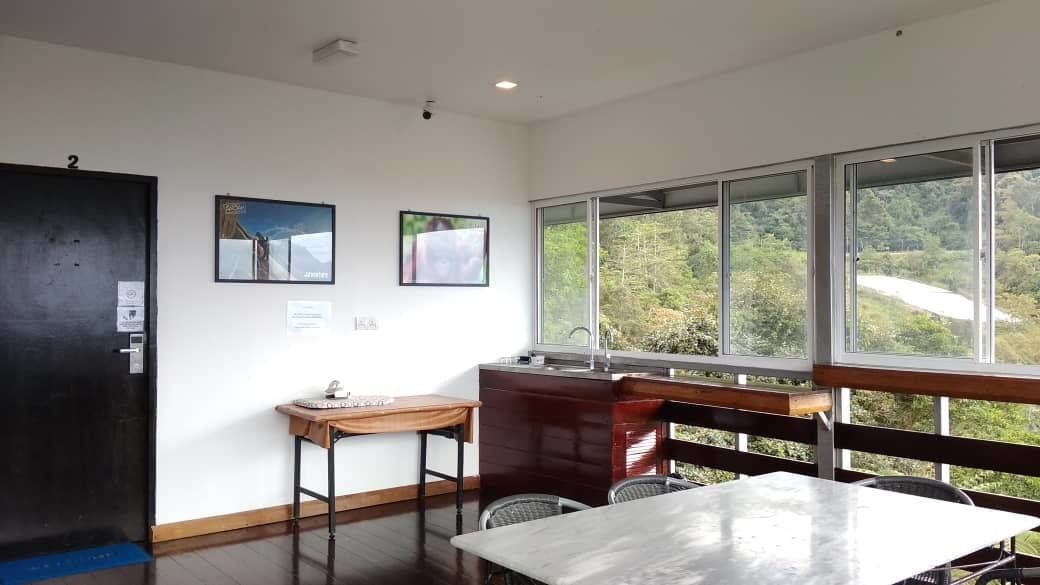 A modern room with a large window, a wooden table, a small desk, and a chair.
