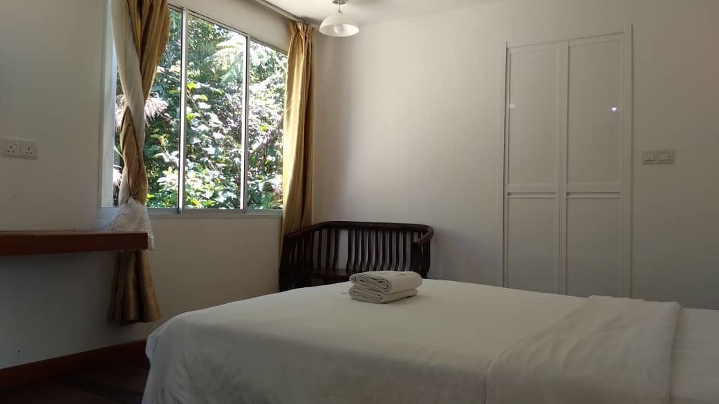 A bedroom with a bed, a window with curtains, a chair, and a wardrobe.