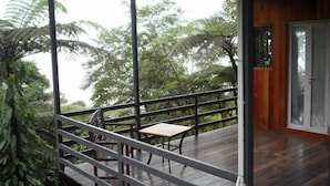 A wooden deck with a table and chairs, surrounded by lush greenery.