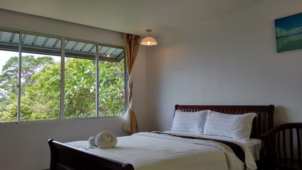 Un dormitorio con cama, ventana con cortinas y vistas al verde exterior.