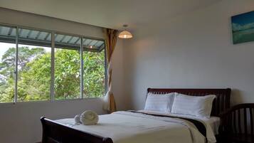 Un dormitorio con cama, ventana con cortinas y vistas al verde exterior.