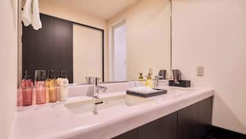 A modern bathroom with a white sink, a large mirror, and various toiletries.
