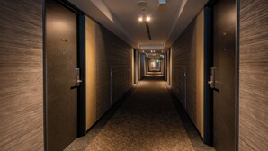 A long, narrow hallway with wooden walls and doors, leading to a bright end.