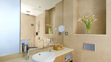 A modern bathroom with a large sink, mirror, and shower.