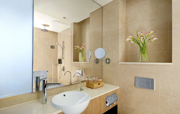 A modern bathroom with a large sink, mirror, and shower.