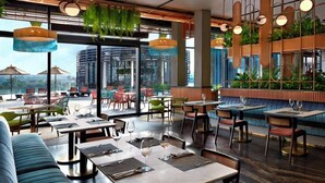 Un restaurante moderno con mesas dentro, ventanas amplias y plantas colgantes.