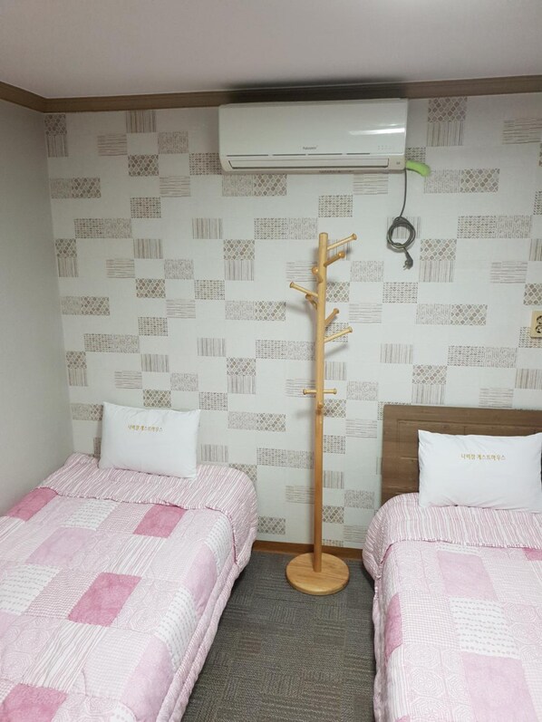 A hotel room with two beds, a wooden coat rack, an air conditioner, and patterned wallpaper. - Nabijam Motel (Yeosu)