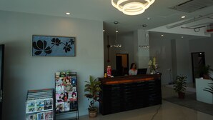 Et moderne receptionsområde med en reception, et stort blomsterkunstværk på væggen og en potteplante.