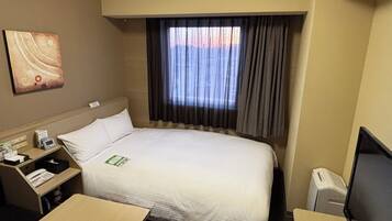 Une chambre d’hôtel avec un lit, un bureau, une télévision et une fenêtre avec des rideaux.