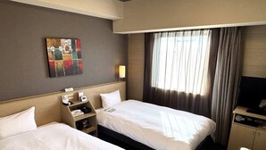 Ein Hotelzimmer mit zwei Betten, einem Fernseher, einem Schreibtisch und einem Bild an der Wand.
