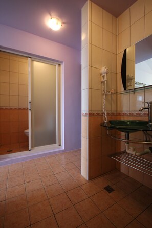 Un baño con cabina de ducha de vidrio, un lavamanos con espejo y un perchero para toallas.