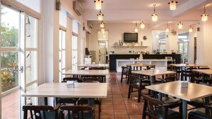 A restaurant with multiple tables and chairs, a counter with a TV, and large windows. - Vanilla Sky (Wujie)