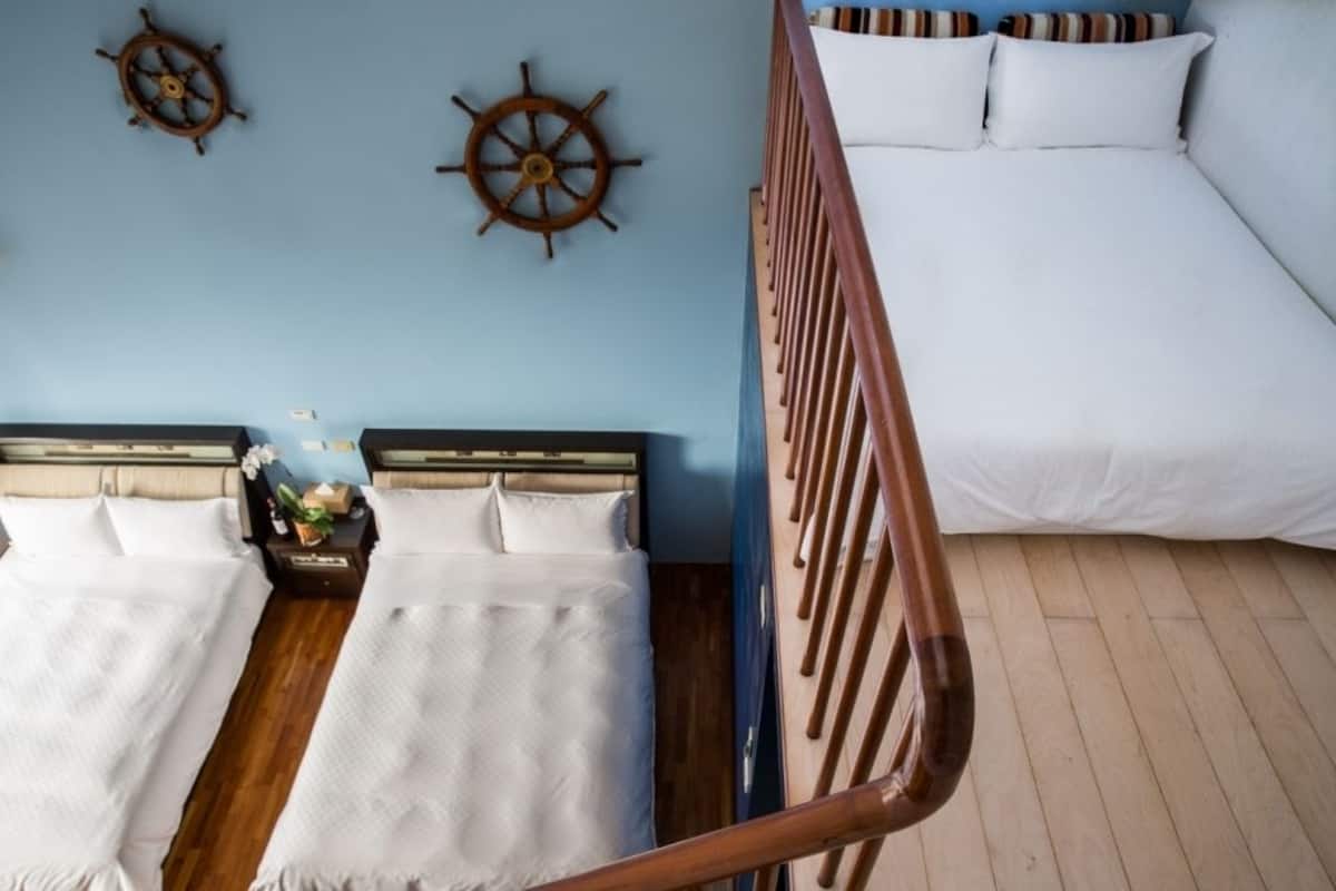 A room with two beds, wooden headboards, and two ship's wheel wall decorations.