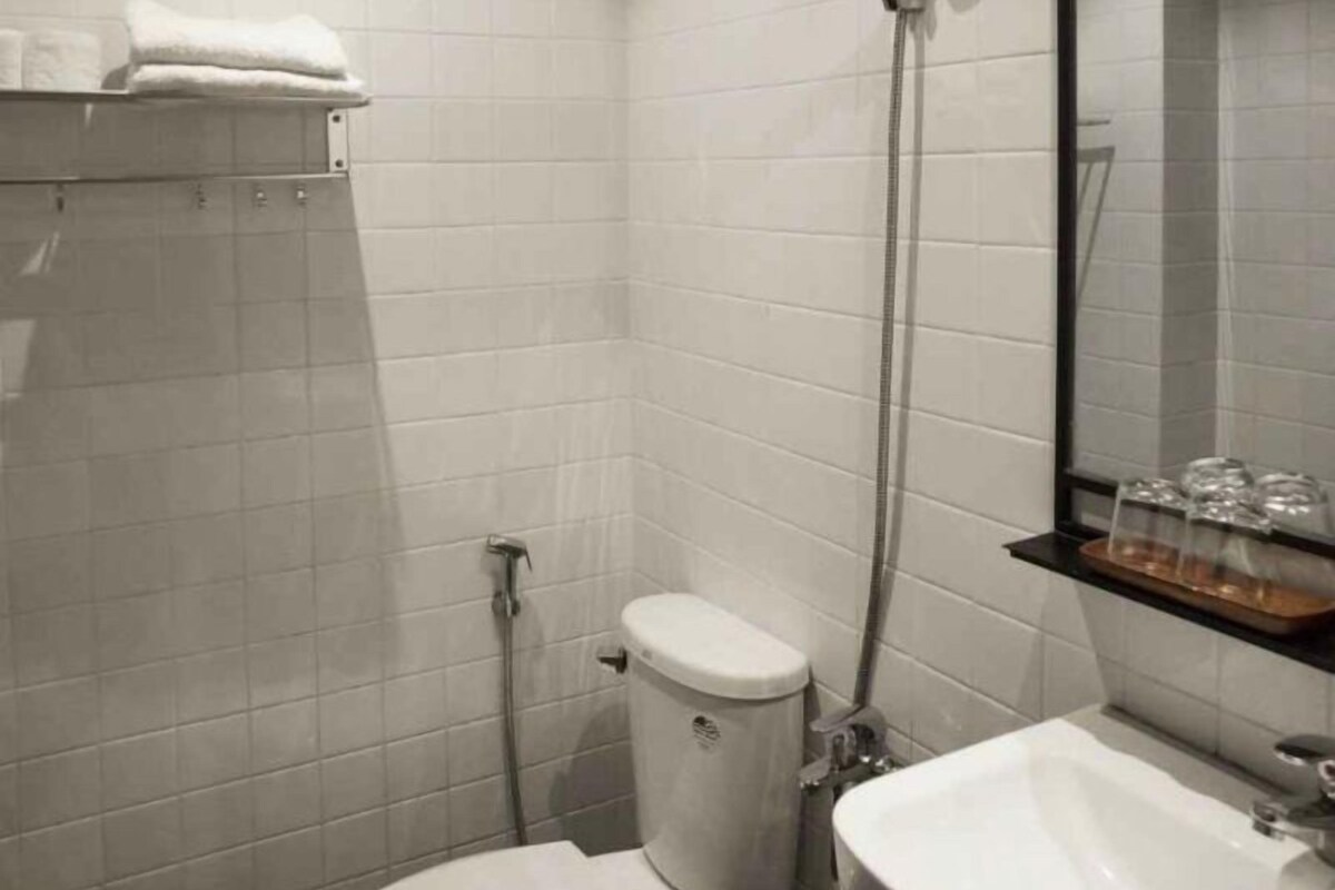Une salle de bain avec des carreaux blancs, des toilettes, une douche, un lavabo et un miroir.