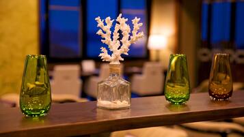 A bar area with three glass bottles on a wooden surface, one containing a white coral-like structure.