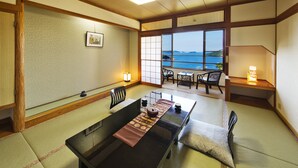 A traditional Japanese room with tatami flooring, a low table with a cushion, a view of the sea, and a sliding door with a view of the ocean. - Toba View Hotel Hanashinjyu (Toba)