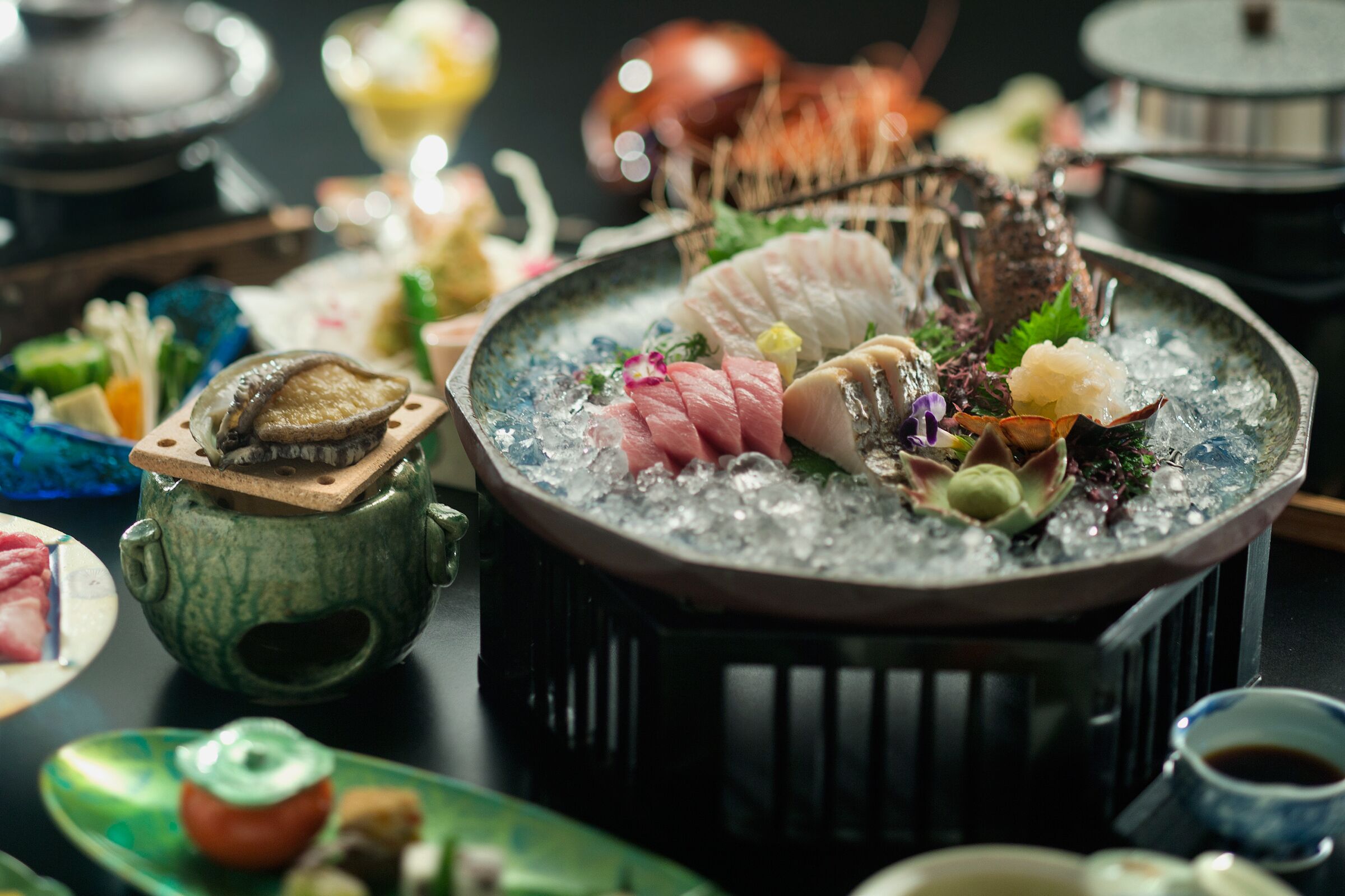 A hot pot with various ingredients and a green ceramic pot on the side.